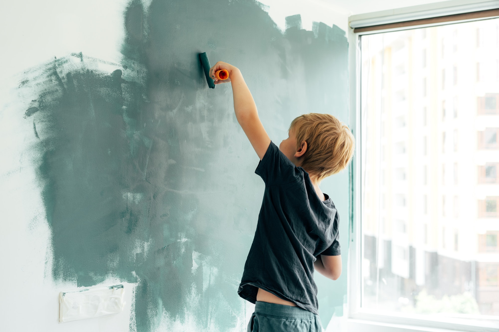 Home improvement. the boy paints the wall in the room with a roller